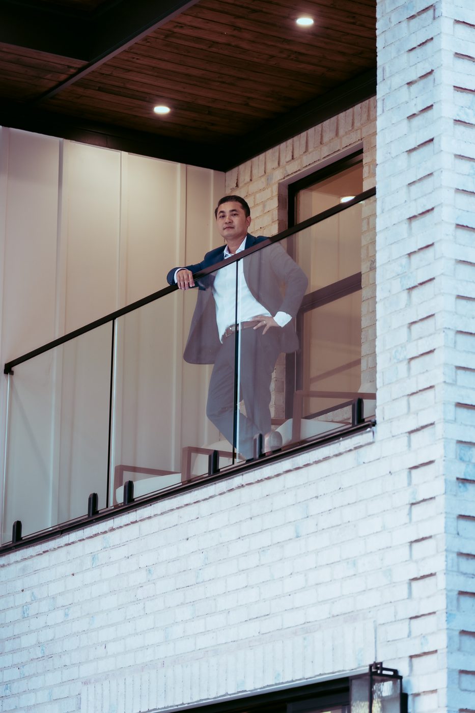 Dewey Luong in a navy suit on a balcony at a luxury home during his brand shoot